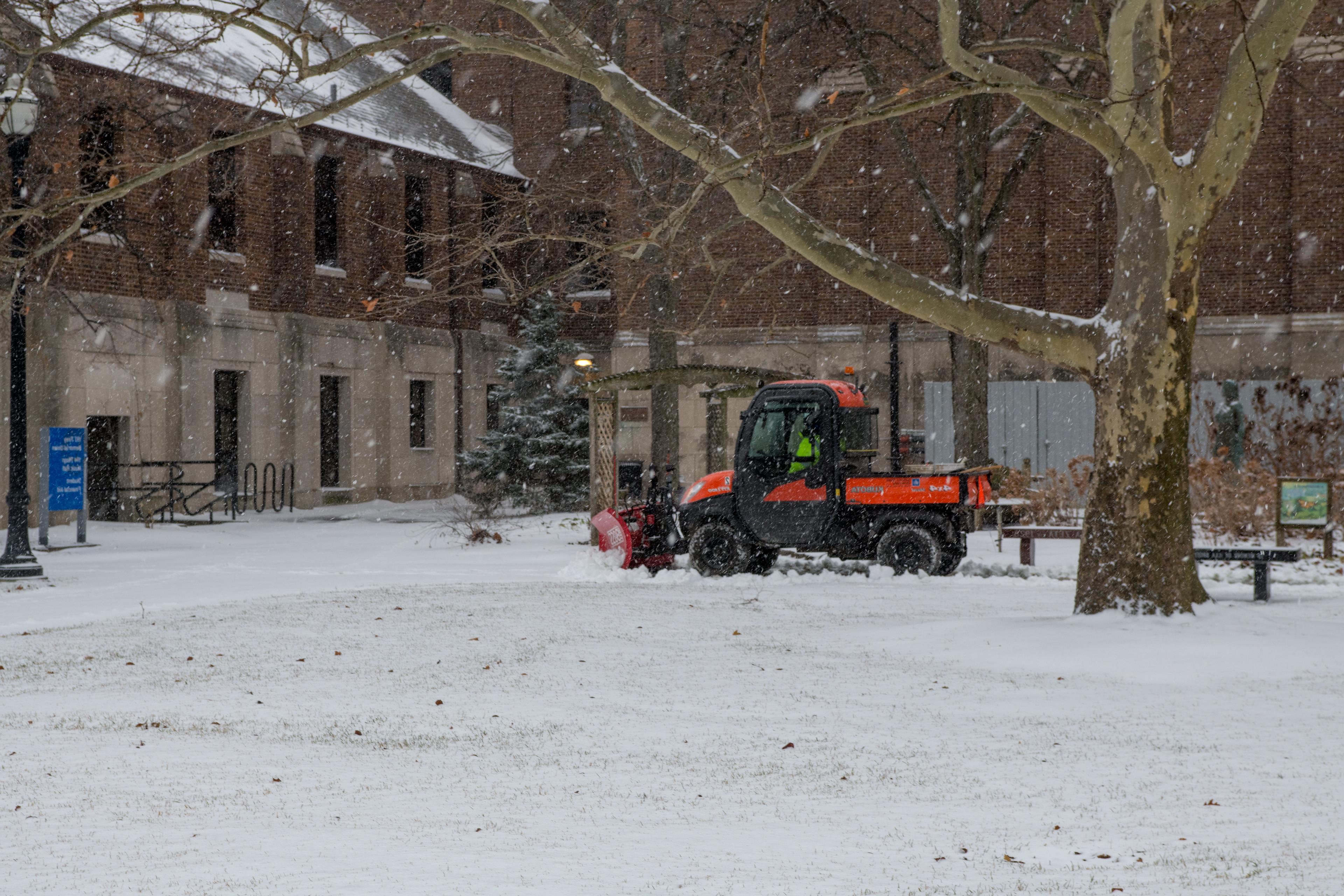 Image of a utility vehicle plowing snow on campus